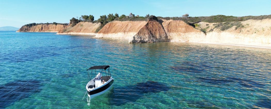 Rental boat anchored below the cliffs on the coast of Kassandra, Halkidiki